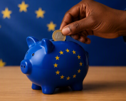 Hand som lägger ett euromynt i en sparbössa med eu-flagga på